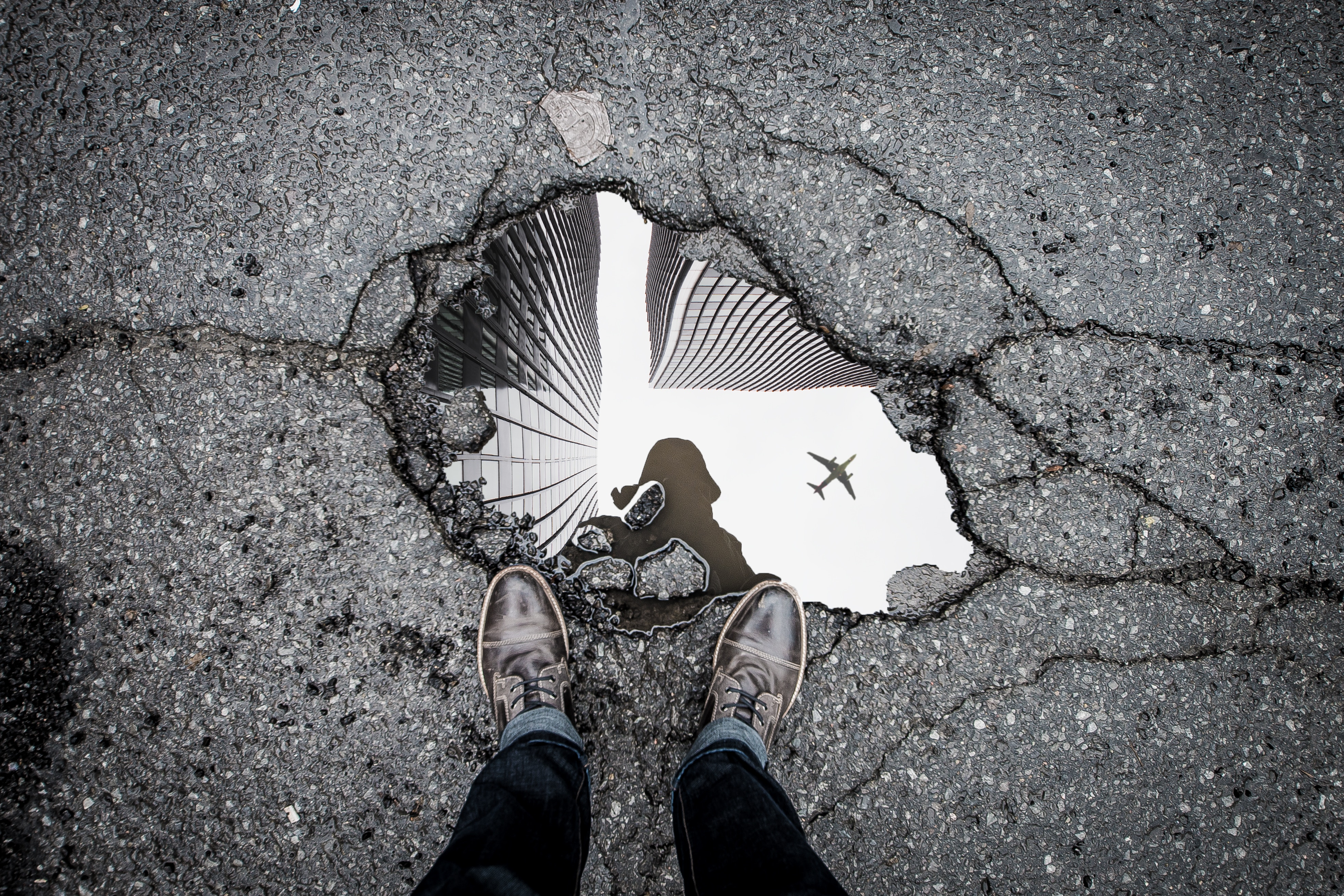 Person standing at a sink hole reflecting the city.
