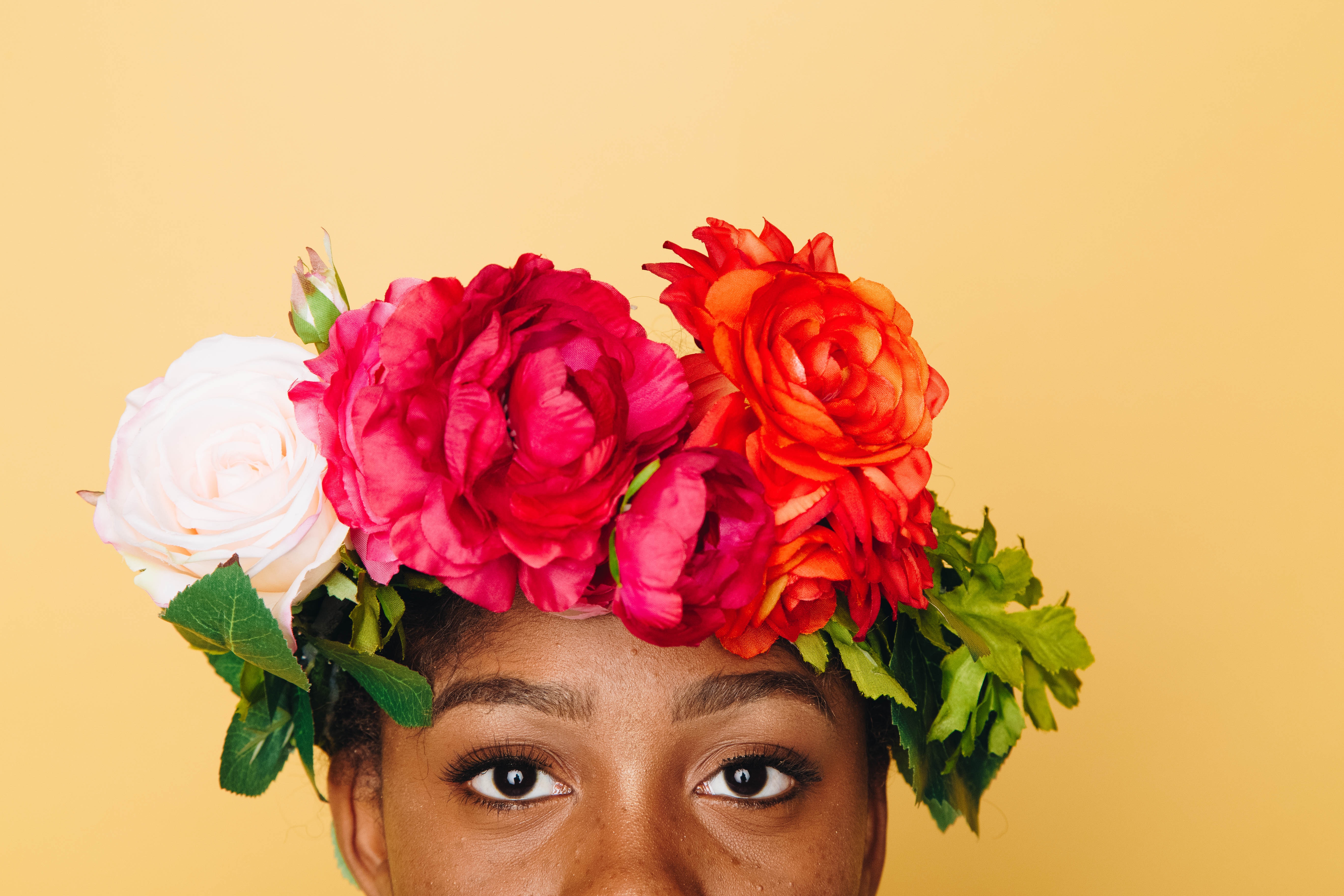 Black woman wearing flower crown with yellow background.